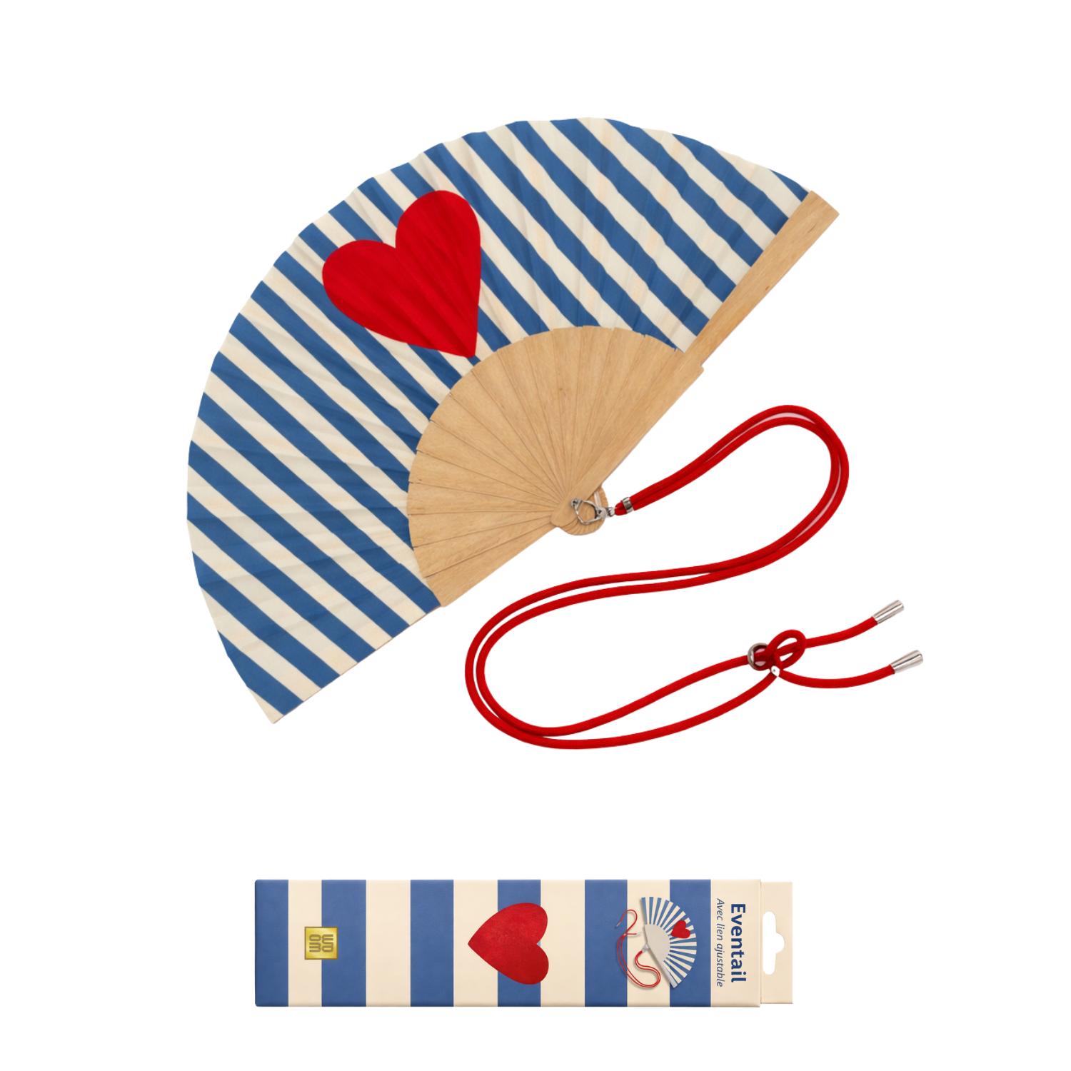 Éventail avec bandoulière présenté dans sa boîte cadeau assortie, au design rayé bleu et crème avec un cœur rouge iconique. Un format élégant, prêt à offrir, qui combine style, fraîcheur et praticité.
